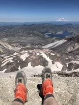 Thomas at the summit after climbing Mount Saint Helens. Spirit lake and Mount Rainier in the distance.