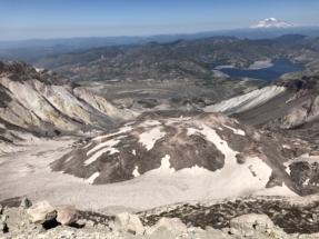 Peering into the crater at the summit after climbing Mount Saint Helens. Spirit lake and Mount Rainier in the distance.